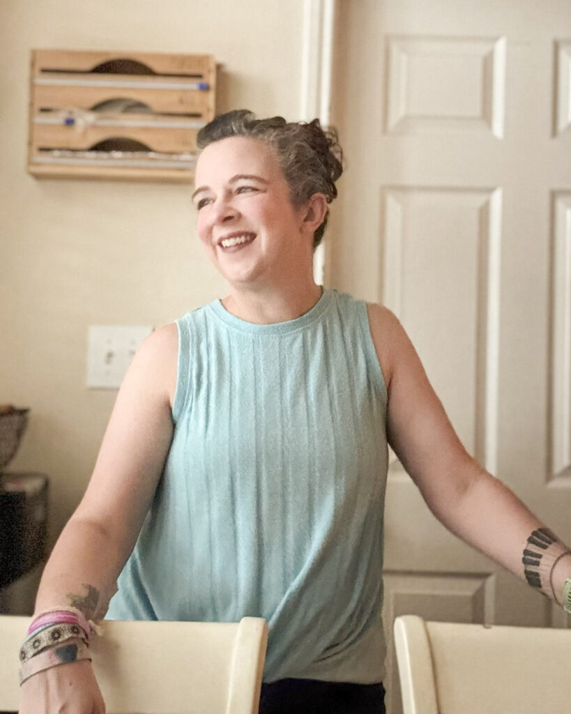 Woman in a blue shirt standing in kitchen laughing